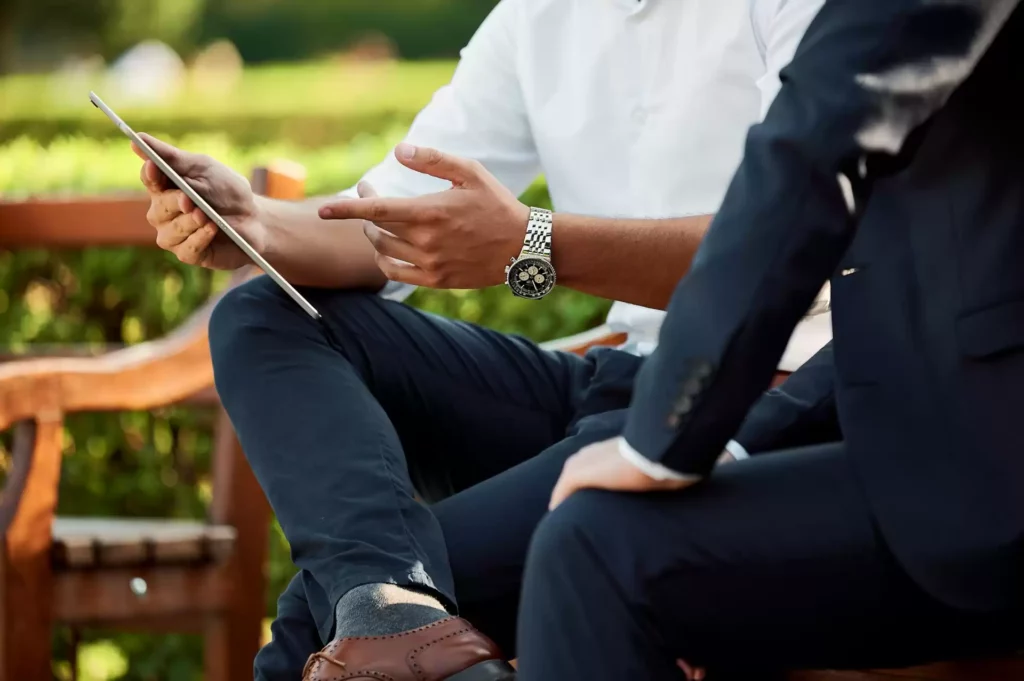 two businessmen sitting at a park bench discussing potential business process management solutions